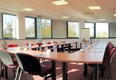 U-shaped conference room with several windows and white and black chairs.