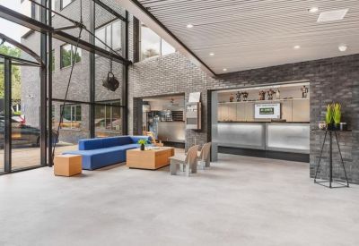 Spacious reception area with a blue sofa, light gray floors, and brick walls.
