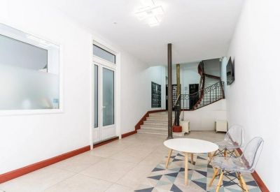 Bright building entrance and lobby area with a staircase and a small seating area.