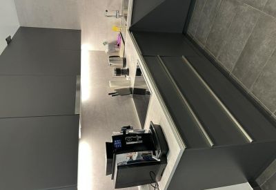 Sleek communal kitchen area with dark grey cabinetry and a professional coffee machine.