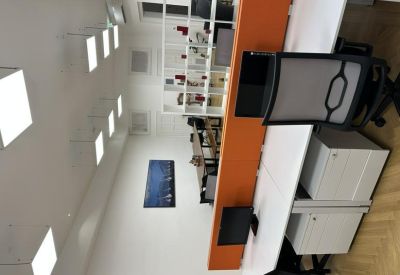 Bright office space with orange privacy screens, white desks, and ergonomic chairs.