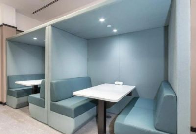 Private blue acoustic meeting booths with white tables and integrated lighting.