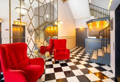 Art deco style reception area with red velvet armchairs, checkered flooring, and a decorative gold partition.