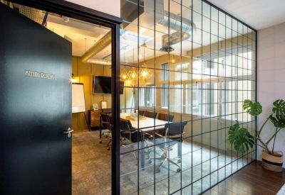 Meeting room with a long table and black chairs, enclosed by a glass-paned wall.
