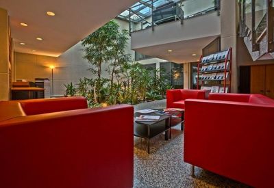 Reception and lounge at 120 rue Jean Jaures, Levallois Perret featuring red armchairs and an indoor garden atrium.