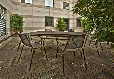Outdoor terrace with a metal dining table and green potted plants.