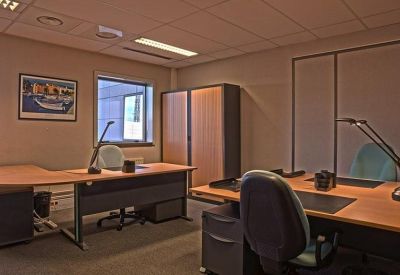 Two-person private office with wooden desks and grey storage cabinets.