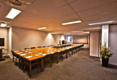 Large meeting room with U-shaped wooden table and modern lighting.