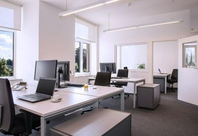 Professional open-plan workspace with multiple white desks and ergonomic chairs.