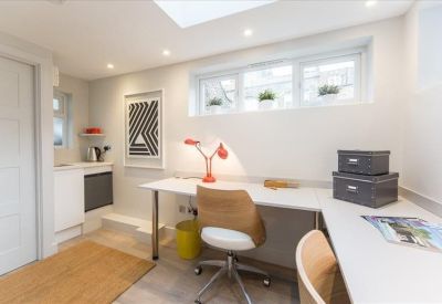 Close-up of a workspace with a desk, red lamp, and geometric wall art.