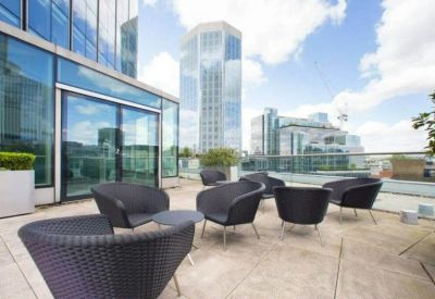 Outdoor lounge area with black wicker chairs overlooking city skyscrapers.