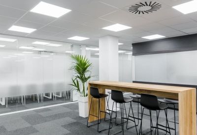 Breakout area featuring a high wooden table with black stools and a tall plant.