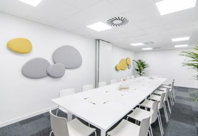 Large conference room with a long white table and numerous grey chairs.