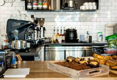 Cafe counter with coffee machine and wooden tray of baked treats.