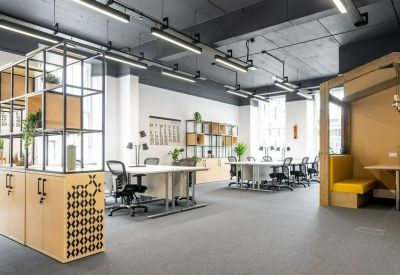 Spacious coworking area with wooden shelving units and industrial-style ceiling lighting.