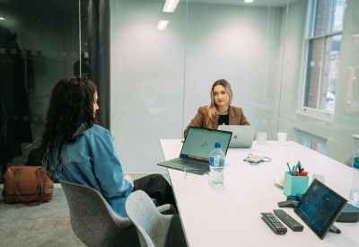 Bright glass-walled meeting room featuring a white table and digital equipment.