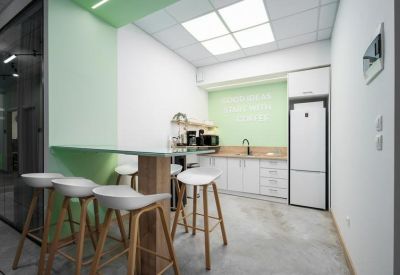 Kitchenette with white cabinetry, wooden counters, and high bar stools.