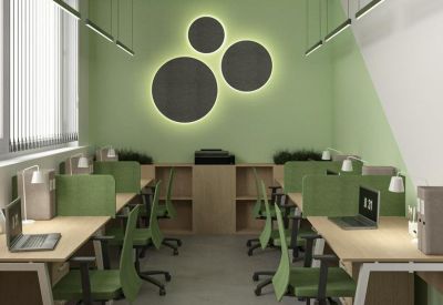 Open-plan office with green ergonomic chairs and circular light wall feature.
