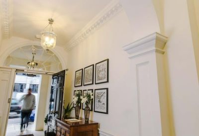 Elegant building entrance hall with ornate crown molding and hanging lanterns.