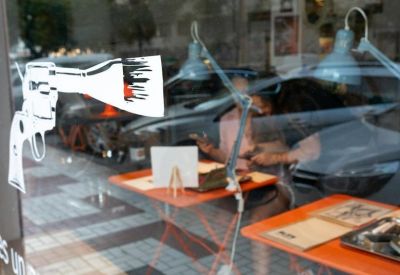 Exterior view of the entrance at 13, Calle San Millán, Local Altallama with a glass facade and gun decal.