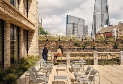 Sunny rooftop terrace with lounge seating and views of The Shard building.