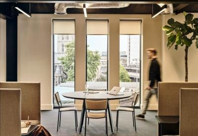 Meeting space with a round table, tall windows, and indoor plants.