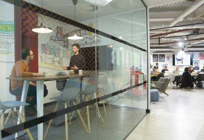 Private meeting room with high stools and a large wall mural seen through glass partitioning.