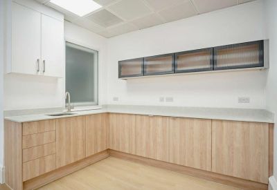 Modern kitchen area with light wood cabinetry and white upper cupboards.