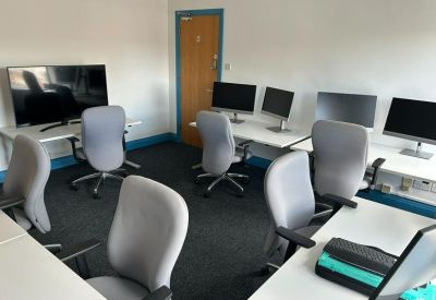 Open-plan workspace with multiple monitors and ergonomic grey chairs.