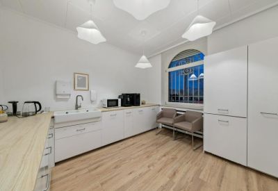 Modern communal kitchen with white cabinetry, wooden countertops, and stylish pendant lights.