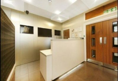 Reception area with a modern white desk and wood-paneled double doors.
