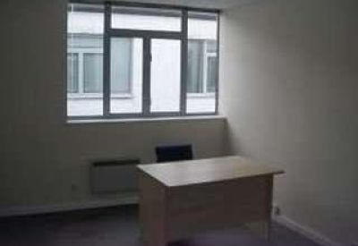 Private office workspace with a wooden desk positioned in front of a large window.