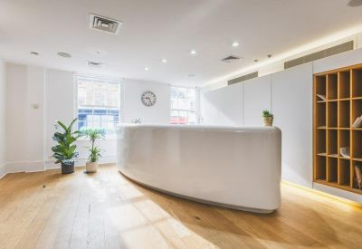 Modern white reception desk with light wood flooring and built-in shelving.