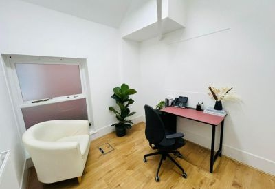 Private office with a red desk, white armchair, and large potted plant.