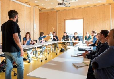 Bright meeting room with a large white table and wooden walls during a presentation.
