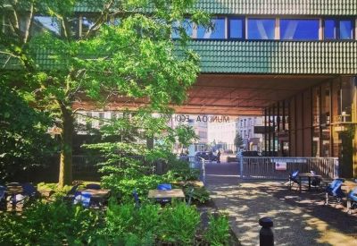 Exterior of the green-tiled facade of 139 A, Turnhoutsebaan surrounded by lush trees and an outdoor patio.