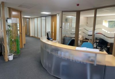 Curved frosted glass reception desk in a brightly lit lobby area.