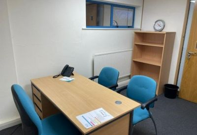 Private office with a wooden desk, blue chairs, and a matching bookshelf.