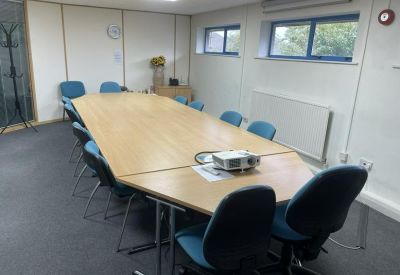 Large meeting room featuring a long wooden conference table and blue chairs.