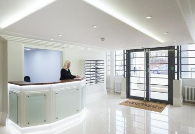 Bright, white minimalist reception area with a modern desk and glass entry doors.