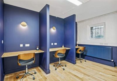 Private work booths with dark blue walls, individual lighting, and ergonomic chairs.