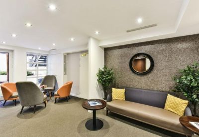 Stylish lounge area with plush grey and orange armchairs and a modern sofa.
