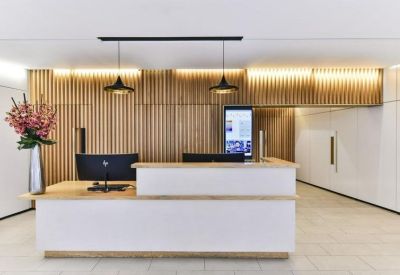 Bright reception area with a minimalist white desk and vertical wood slat wall detailing.