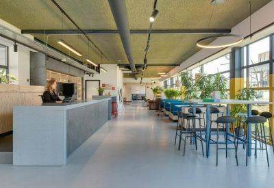Long reception desk and hallway with blue cafe booths and indoor plants.