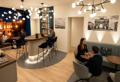 Vibrant breakout area with a central bar, navy velvet stools, and modern lighting.