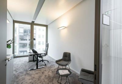 Modern single-person office with a grey armchair and large windows.
