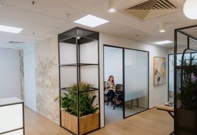 Stylish breakout area with green plants, a glass partition, and warm wood flooring.