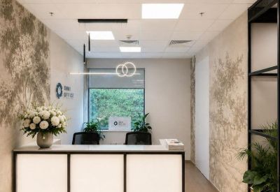 Sleek minimalist reception desk with illuminated panels and a floral arrangement.