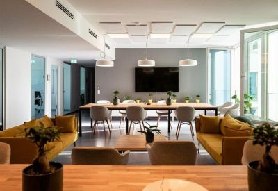 Spacious communal lounge with mustard yellow sofas and a long communal wooden table.