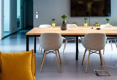 Close-up of a long wooden meeting table with grey designer chairs and pendant lighting.